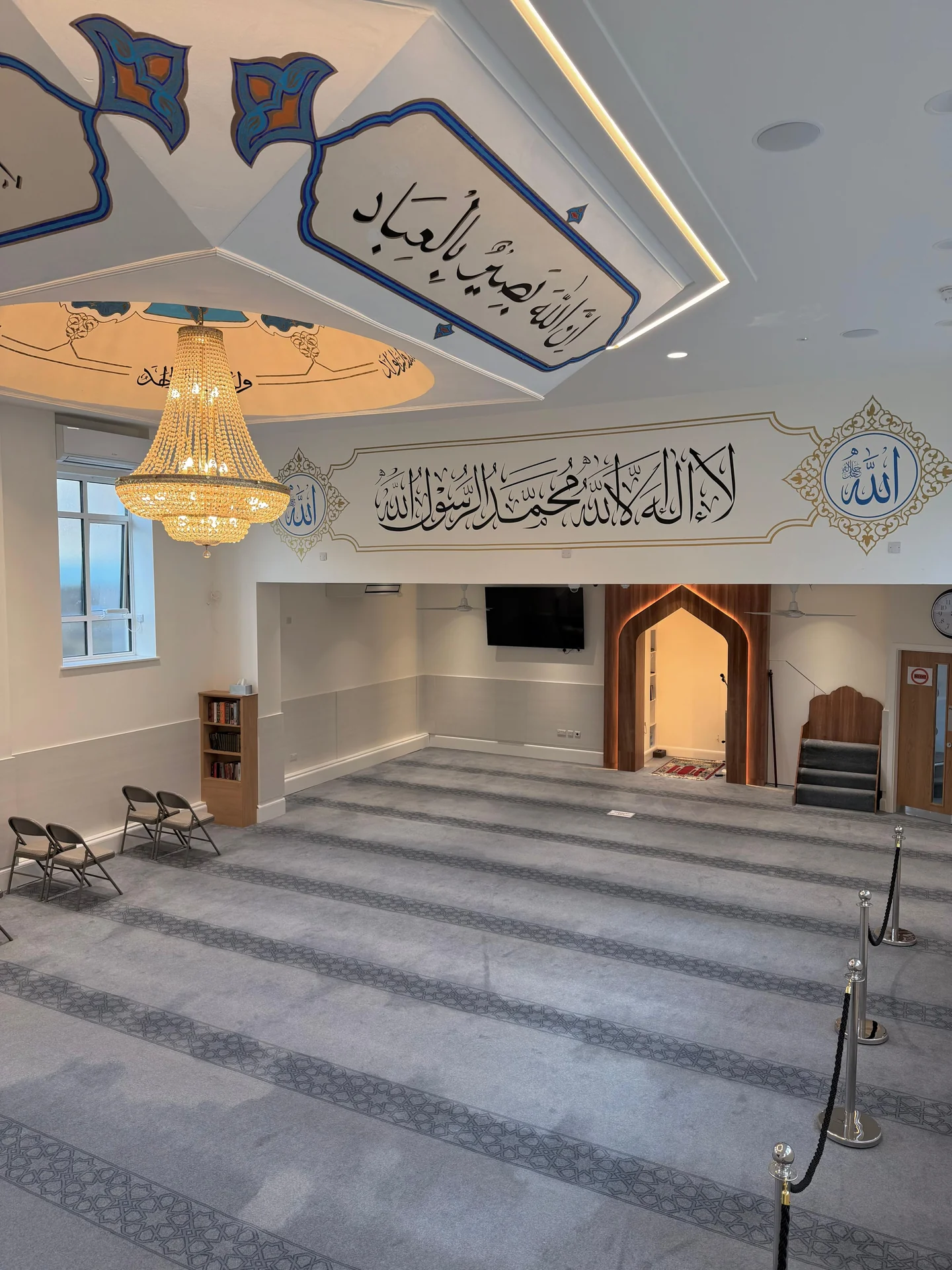 Arabic calligraphy across mosque walls and ceiling above the prayer hall