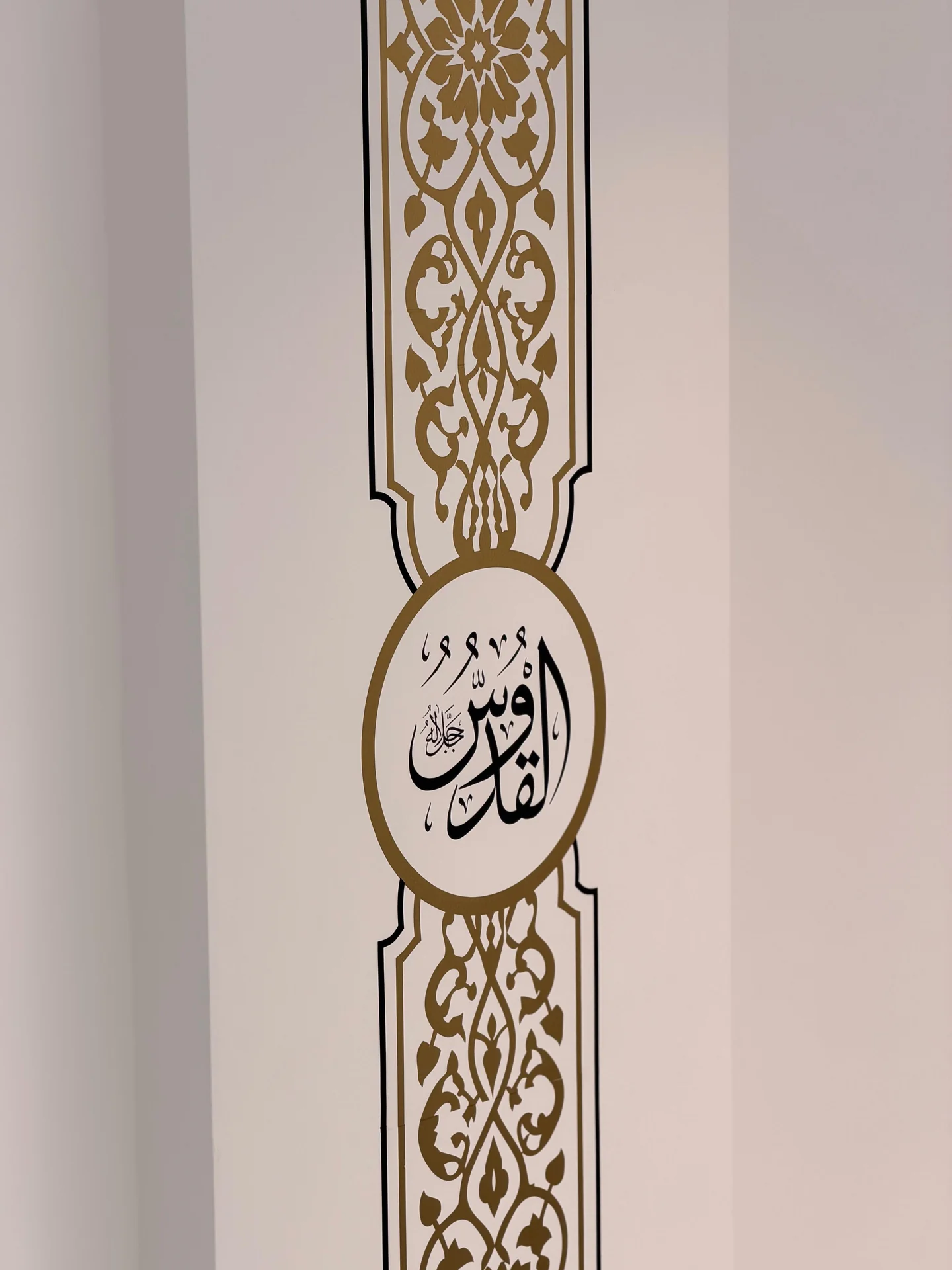 Close-up of an Arabic calligraphy medallion within a gold wall panel