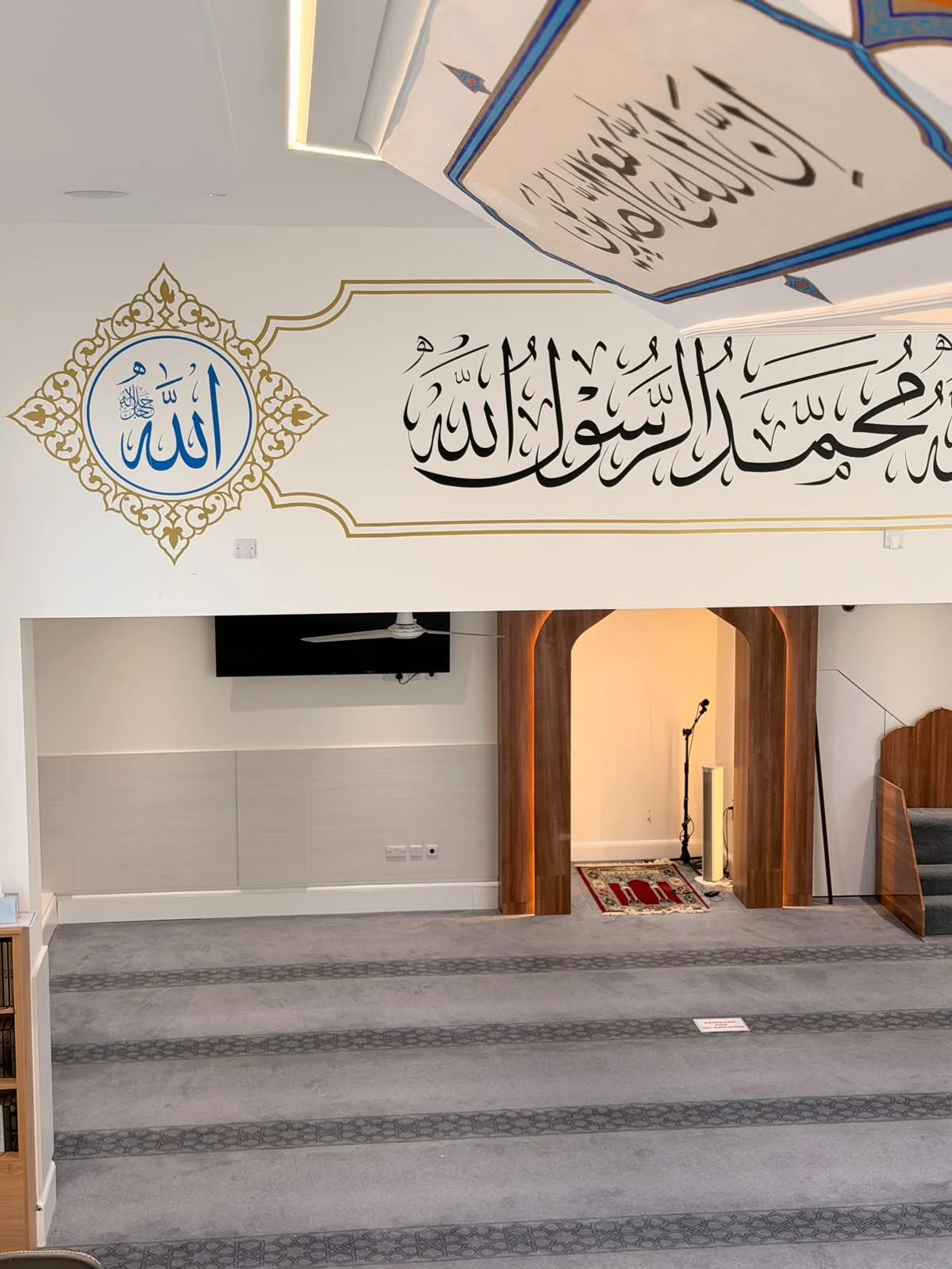Arabic calligraphy frieze and gold detailing above the prayer space